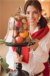 Woman holding fruit under glass cover (Christmas table decoration)