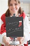 Young woman holding slate with the words Merry X-mas (for table)