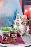 Woman pouring peppermint tea into glasses