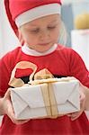 Small girl in Father Christmas costume holding gift