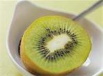 Half a kiwi fruit in bowl with spoon