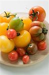 Various types of tomatoes on wooden plate