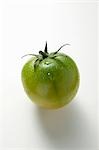 Green tomato with drops of water