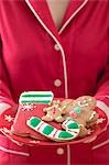 Woman holding plate of Christmas biscuits