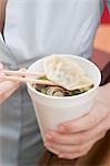 Woman holding paper cup of Asian noodle soup