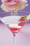 Martini with strawberry in glass, rose in background