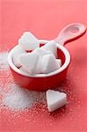 Heart-shaped sugar lumps in red measuring cup