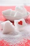 Sugar cube with red heart and heart-shaped sugar lump