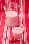 Strawberry milk in glass with straw, glass jug, strawberry