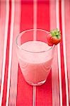 Strawberry milk in glass with fresh strawberry on rim