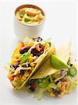 Tacos filled with beans & sweetcorn, vegetable dip in small bowl