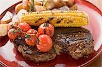 Grilled steak with corn on the cob, cherry tomatoes, potatoes