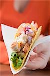 Woman holding chicken taco on paper napkin