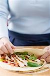 Folding a tortilla over chicken filling