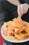 Woman reaching for nachos with melted cheese on plate