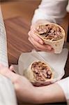 Femme manger un burrito en lisant le journal