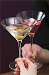 Hands clinking glass of Martini & glass of Cosmopolitan