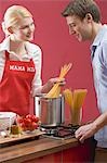 Couple cooking spaghetti with tomatoes