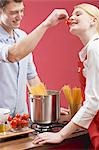 Couple cooking spaghetti with tomatoes