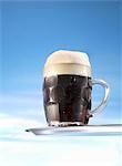 Dark beer in glass mug on tray