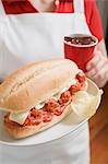 Woman holding meatball sandwich and cup of cola
