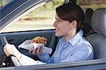 Young woman eating croissant while driving
