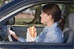 Jeune femme manger des croissants en voiture
