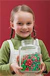 Small girl holding jar of chocolate beans