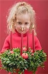 Small girl holding Advent wreath with burning candles