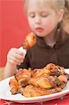 Little girl eating chicken drumstick