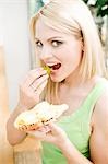 Woman biting into grape and holding cheese sandwich