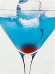 Blue Curaçao cocktail with cocktail cherry & ice cube