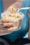 Woman eating pasta salad out of plastic tub