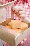 Woman holding box of cornbread (pieces)