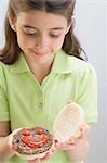 Little girl holding opened burger with ketchup face