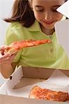 Kleines Mädchen hält Stück Pizza über Pizza-Schachtel