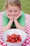 Fille regardant les fraises dans une passoire