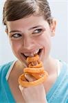 Young woman biting into deep-fried onion ring on index finger