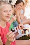 Girls eating chocolate-coated marshmallows out of doors