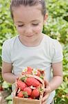 Kleines Mädchen hält Korb mit Erdbeeren
