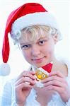 Girl in Father Christmas hat holding Father Christmas biscuit