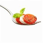 Tomato slices with mozzarella and basil on fork