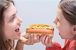 Frau und Mädchen, die von beiden Enden der gleiche Hotdog Essen