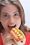 Woman eating a hot dog with mustard