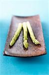 Three spears of green asparagus in wooden dish