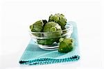 Several green patty pan squashes in glass bowl on table mat