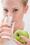 Frau holding Apfel und Glas Wasser trinken