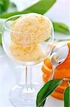 Two scoops of orange ice cream in a glass