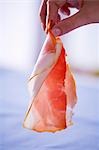 Woman holding a slice of raw ham in her hand