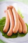 Five frankfurters on a lettuce leaf